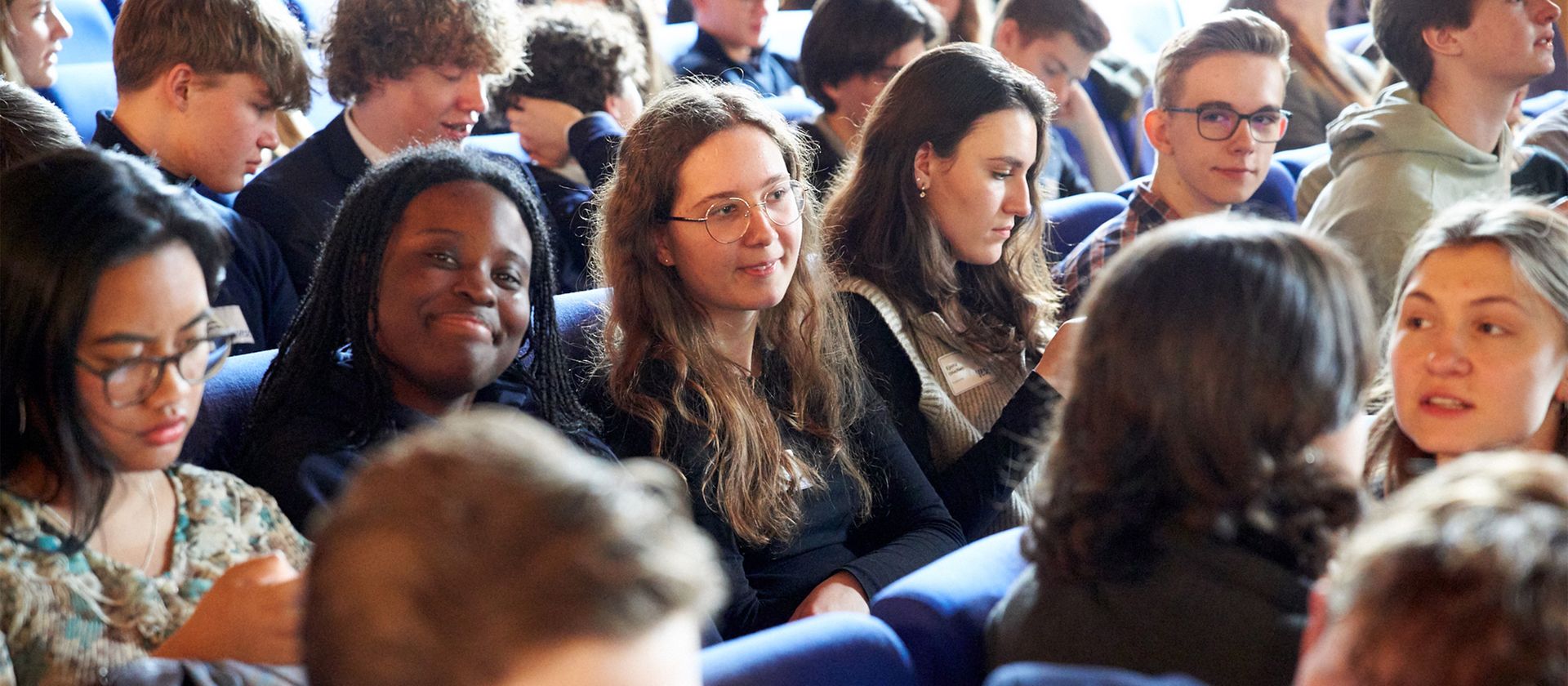 Gruppe von Menschen sitzt dicht nebeneinander und schaut in eine Richtung